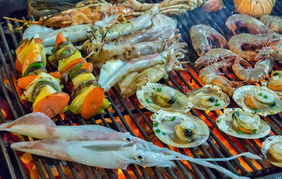 Assorted seafood on the grill with flames closeup of delicious grilled sea food