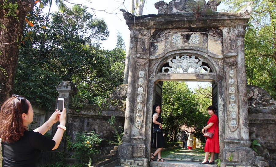 travelers take photos outside the an hien garden house